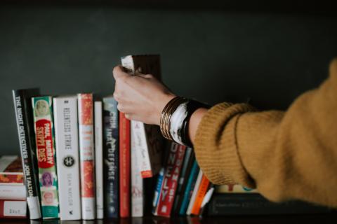 hand reaching for books on shelf