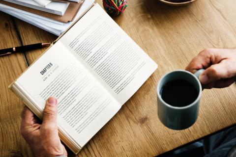 hands holding book and coffee mug