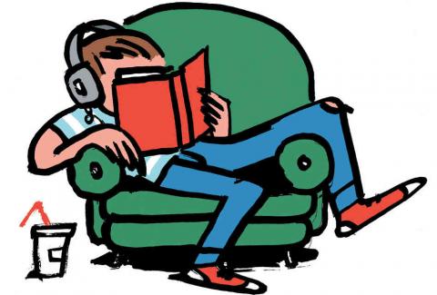 Teen with headphones reading a book in a recliner