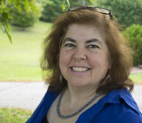 Image of woman with reddish shoulder length hair wearing a blue blouse.