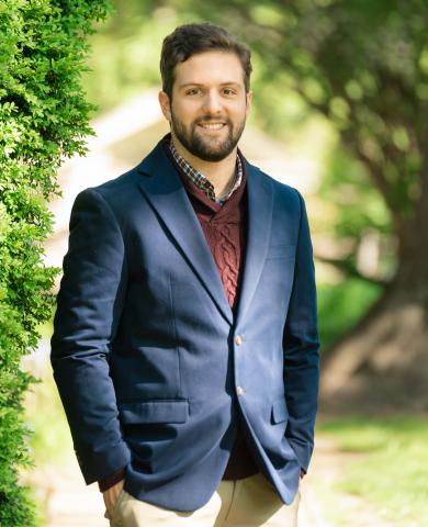 Image of a man with brown hair, brown beard, and a blue sportscoat. 