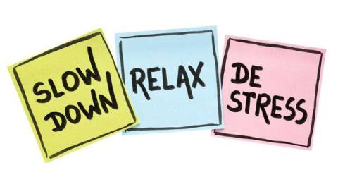 post-it notes in pastel colors with slow down, relax and de-stress written on them in black writing